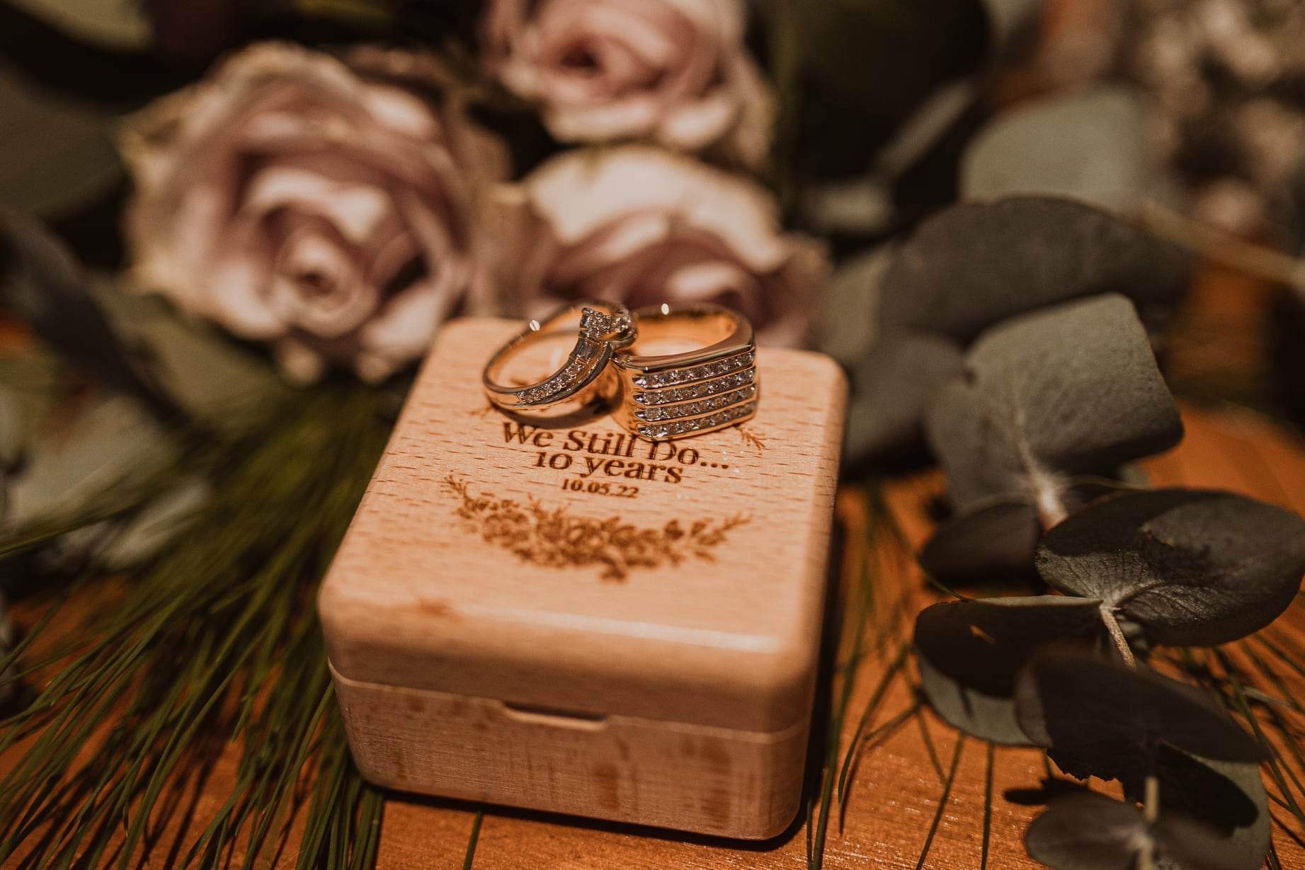 Wedding rings in a personalised wooden box surrounded by dusty rose blooms and eucalyptus