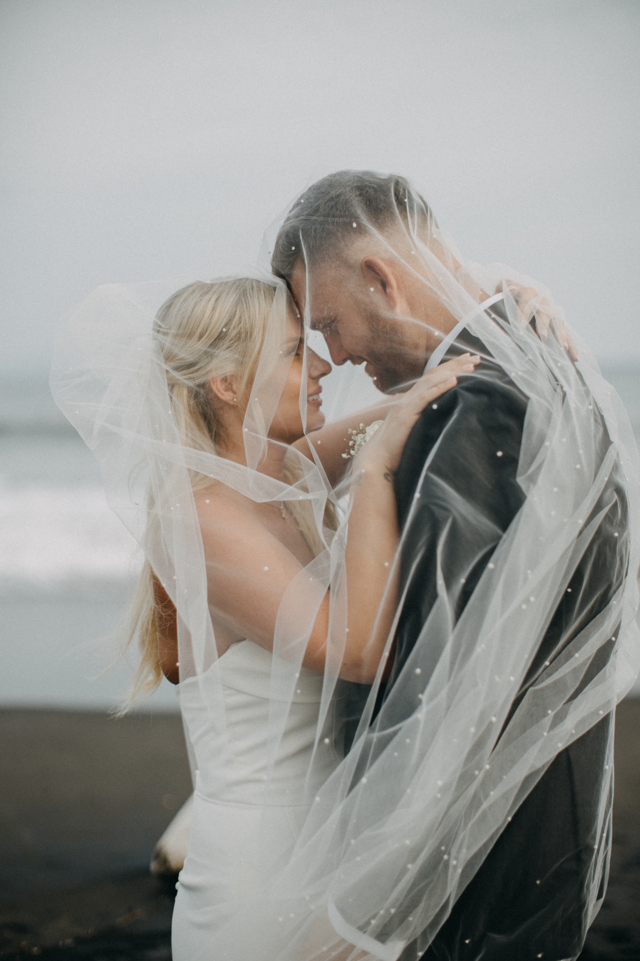 Bride and groom sharing an intimate moment beneath a delicate veil on the Gold Coast
