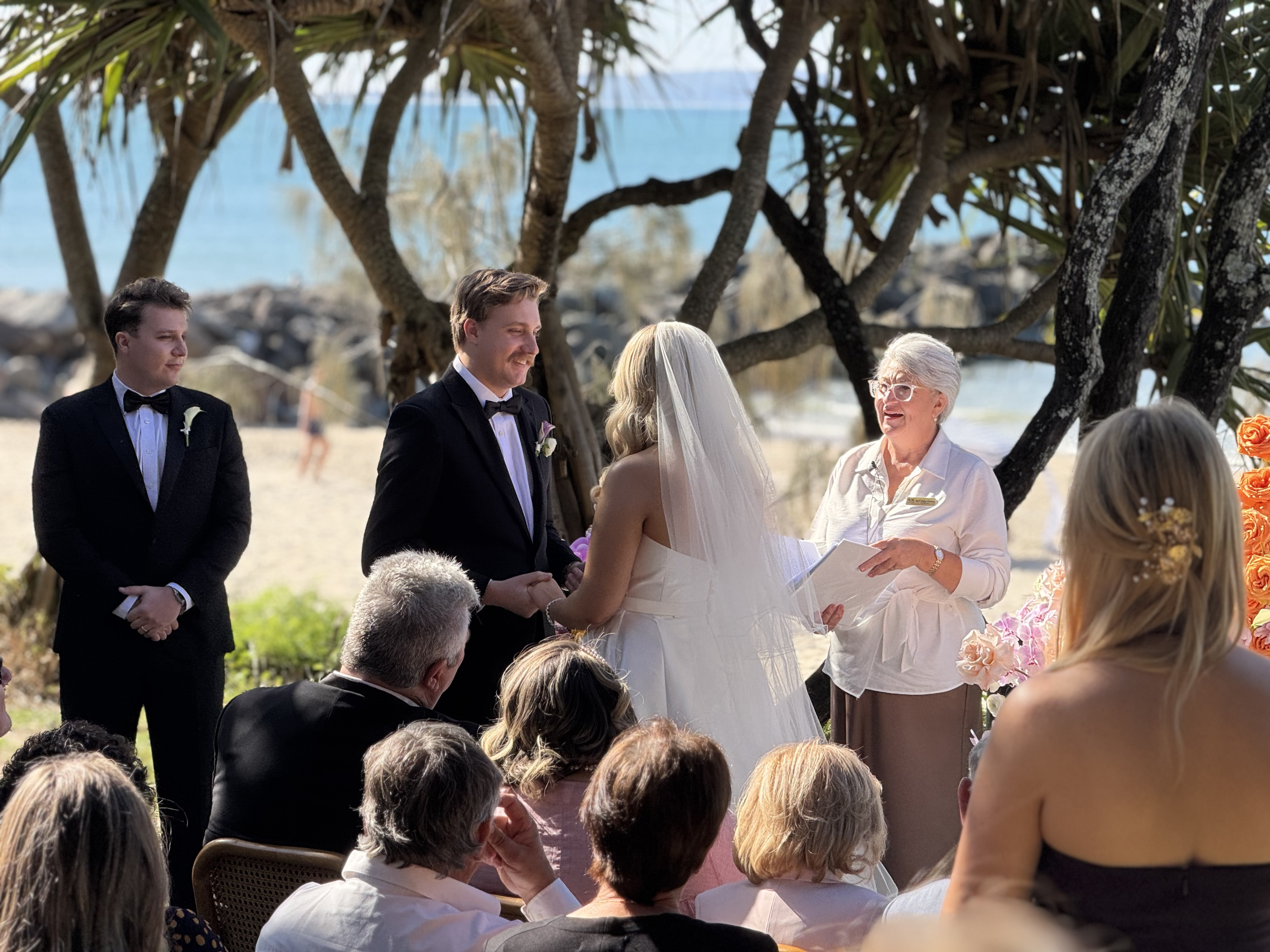 Beach wedding ceremony at sunset with the couple exchanging vows by the ocean