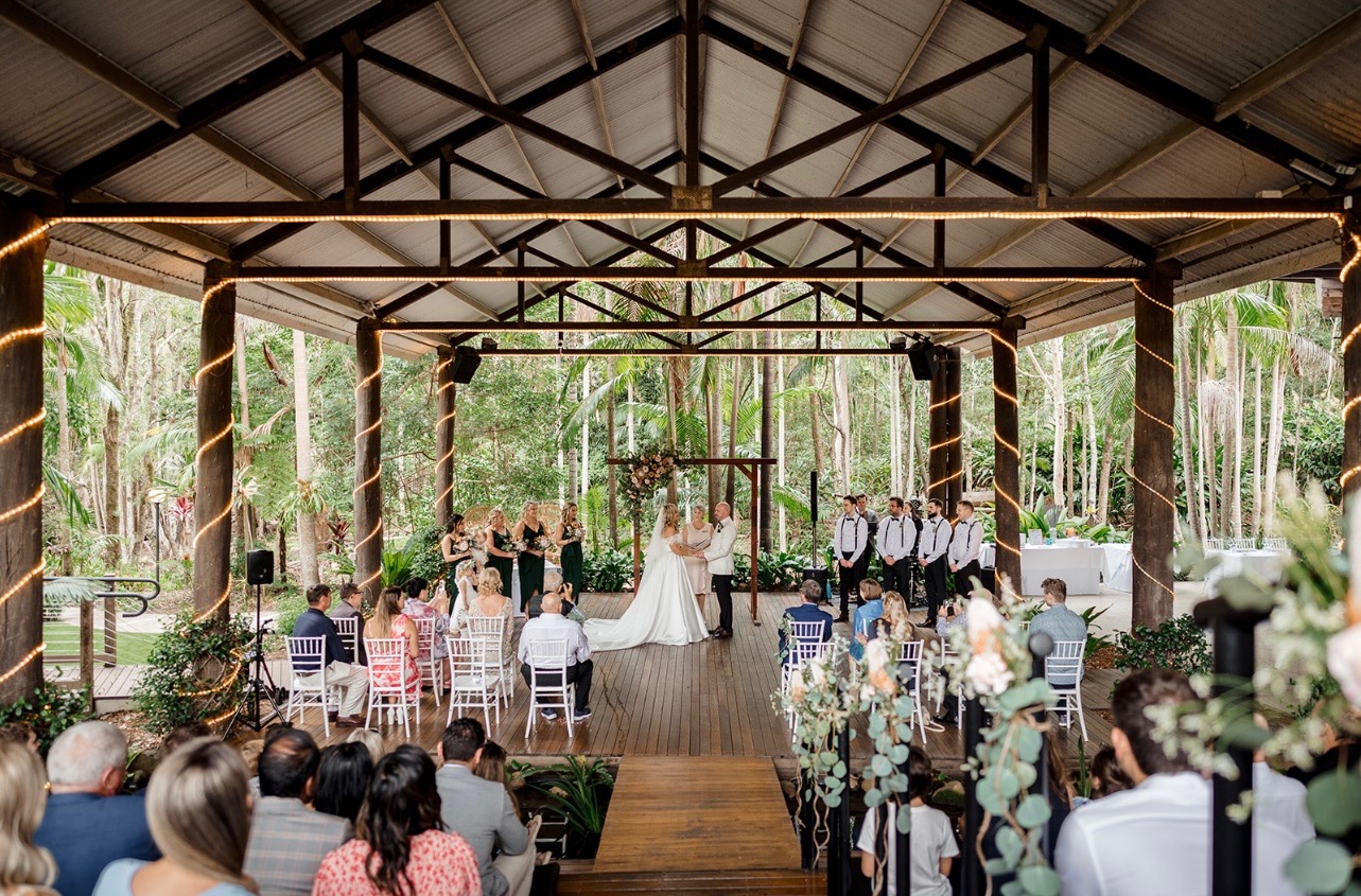 Wedding ceremony in a beautiful open-air pavilion surrounded by tropical greenery and guests