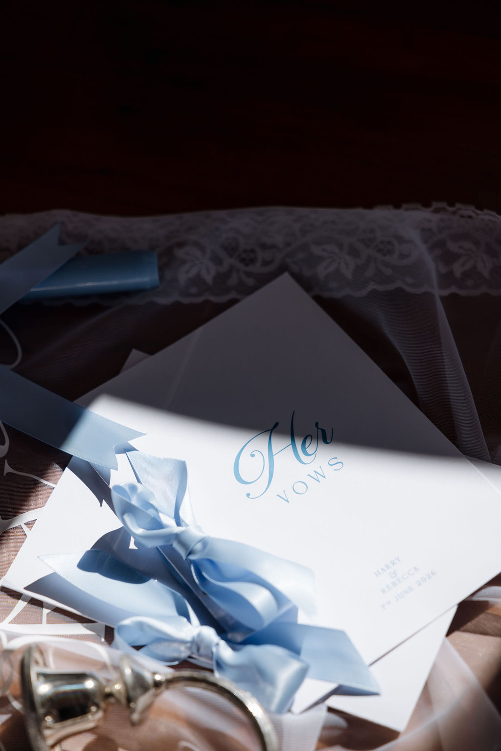 Personalised 'Her Vows' booklet tied with pale blue ribbon, resting on lace